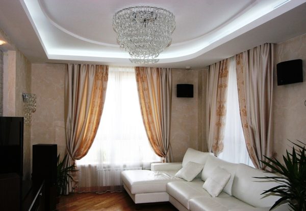 Белый коженый диван в гостиной с двумя окнами 